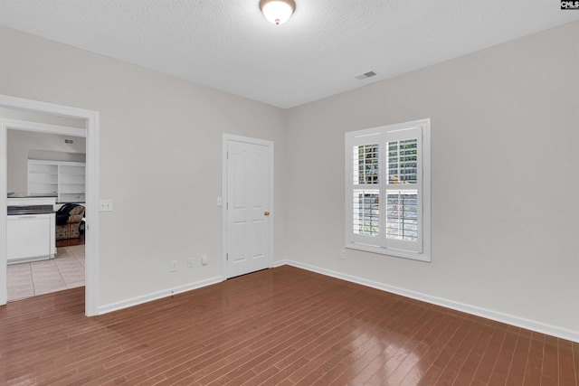 unfurnished room with hardwood / wood-style flooring and a textured ceiling