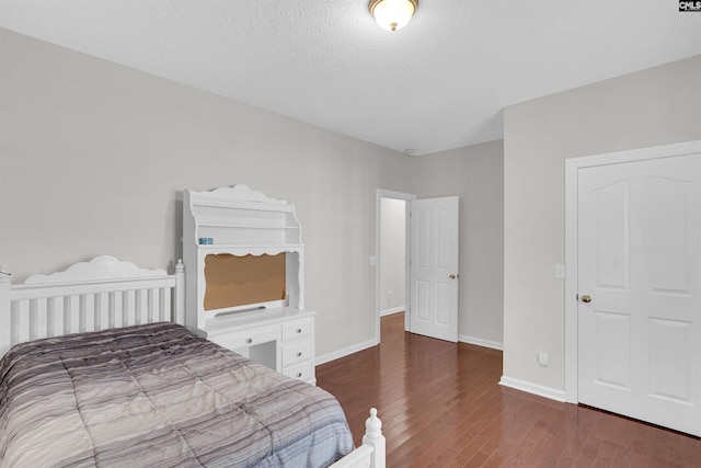 bedroom with dark hardwood / wood-style floors and a textured ceiling