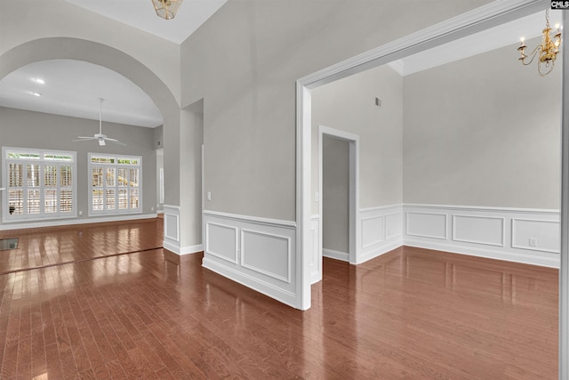 empty room featuring ceiling fan with notable chandelier and hardwood / wood-style floors