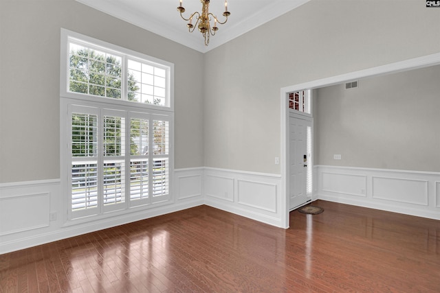 spare room featuring ornamental molding, dark hardwood / wood-style floors, and an inviting chandelier