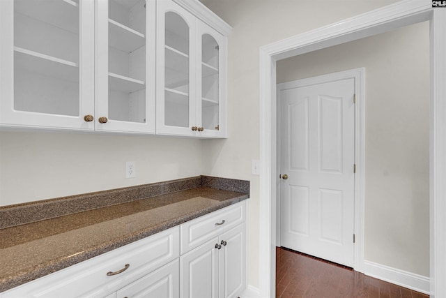 bar with white cabinetry, dark wood-type flooring, and dark stone counters