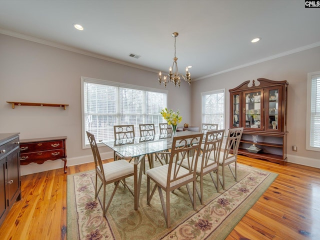 dining room featuring ornamental molding, an inviting chandelier, and light hardwood / wood-style flooring