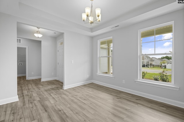 empty room featuring a chandelier and light hardwood / wood-style floors