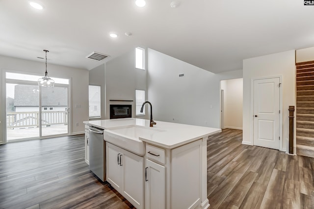 kitchen with sink, white cabinetry, decorative light fixtures, stainless steel dishwasher, and an island with sink