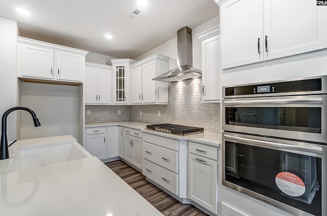 kitchen featuring dark wood-type flooring, wall chimney exhaust hood, sink, white cabinetry, and stainless steel appliances