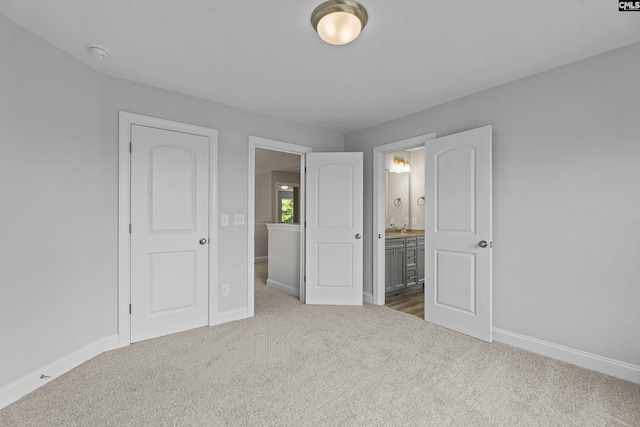 unfurnished bedroom featuring ensuite bathroom and carpet flooring