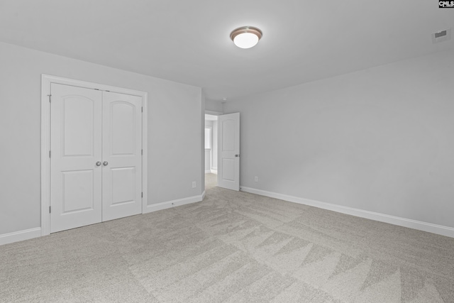 unfurnished bedroom with a closet and light carpet