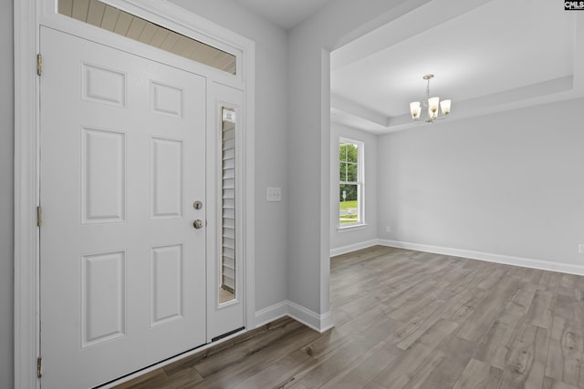 entryway featuring hardwood / wood-style floors, a tray ceiling, and a notable chandelier