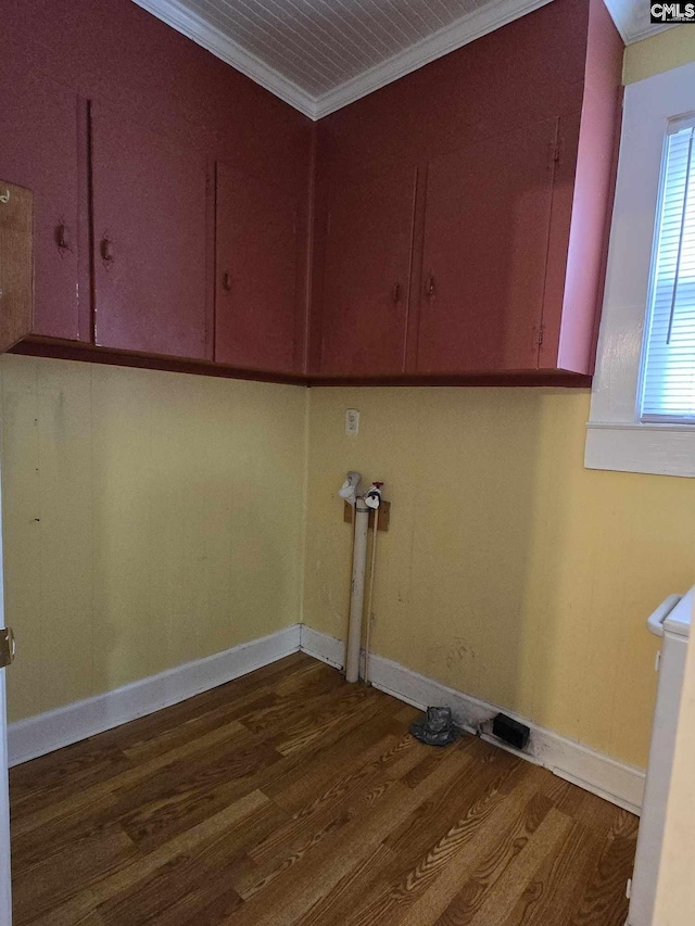 laundry room featuring crown molding, dark wood-type flooring, and cabinets