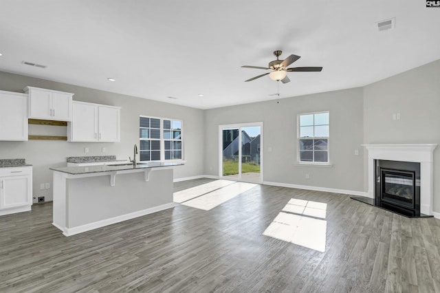 kitchen featuring a breakfast bar, white cabinetry, sink, a kitchen island with sink, and light hardwood / wood-style flooring