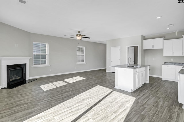 kitchen with hardwood / wood-style floors, white cabinetry, sink, ceiling fan, and a center island with sink