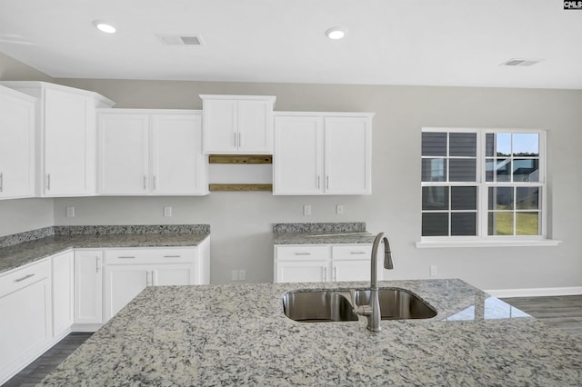 kitchen featuring sink, white cabinets, and light stone counters