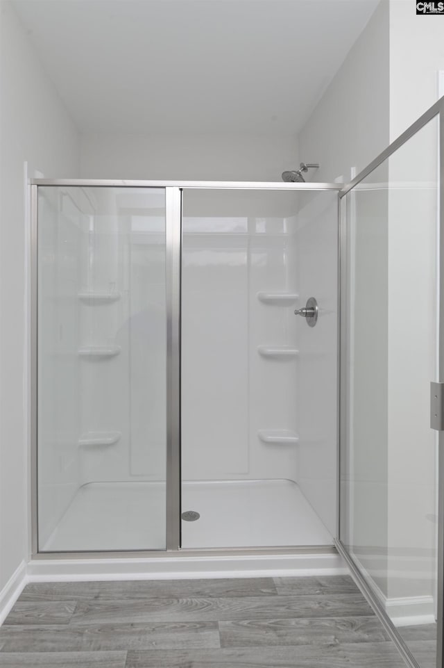 bathroom with an enclosed shower and hardwood / wood-style flooring