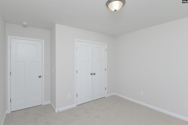 unfurnished bedroom with light colored carpet and a closet