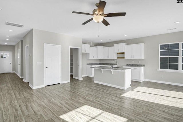 kitchen featuring white cabinetry, light hardwood / wood-style flooring, an island with sink, and ceiling fan