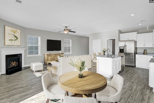 dining room with sink, light hardwood / wood-style flooring, and ceiling fan