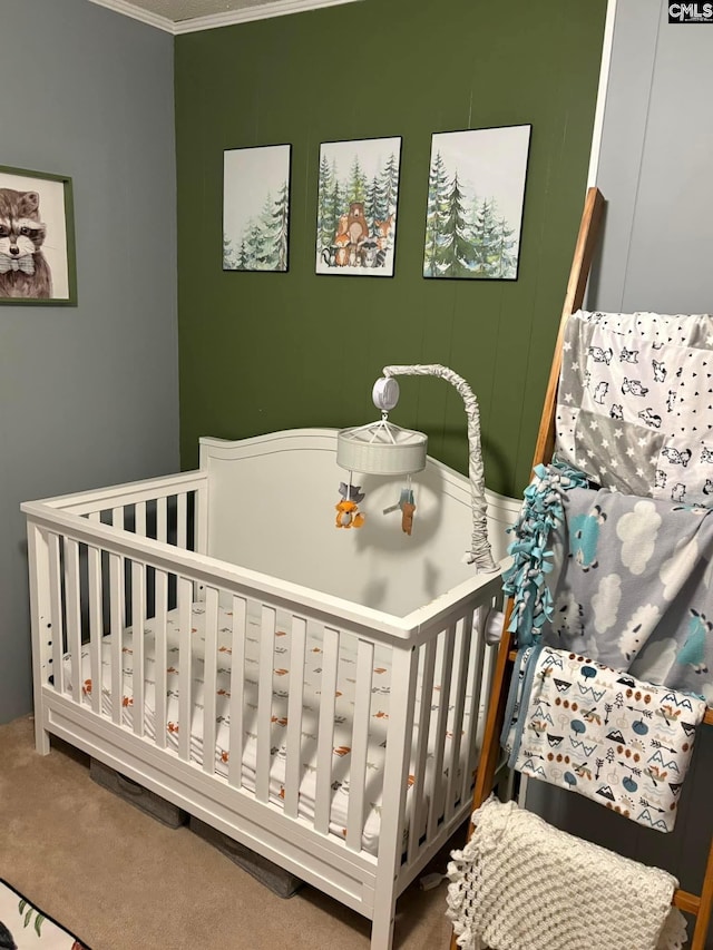 carpeted bedroom featuring ornamental molding and a nursery area