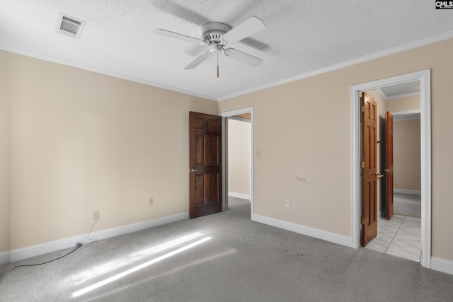 unfurnished bedroom with ceiling fan, ornamental molding, light carpet, and a textured ceiling