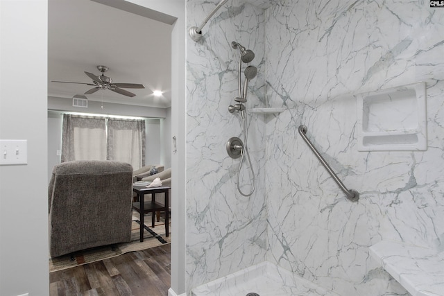 bathroom with hardwood / wood-style flooring, a tile shower, and ceiling fan