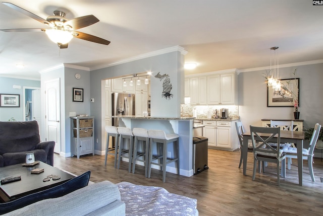 living room featuring hardwood / wood-style flooring, crown molding, and ceiling fan with notable chandelier