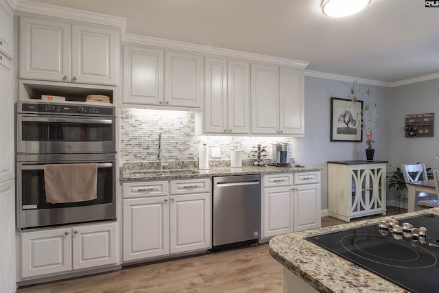 kitchen with crown molding, white cabinetry, stainless steel appliances, light hardwood / wood-style floors, and decorative backsplash