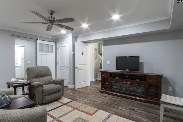 living room with ceiling fan, ornamental molding, a barn door, and dark hardwood / wood-style flooring