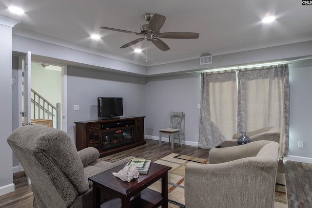 living room featuring dark wood-type flooring, ornamental molding, and ceiling fan