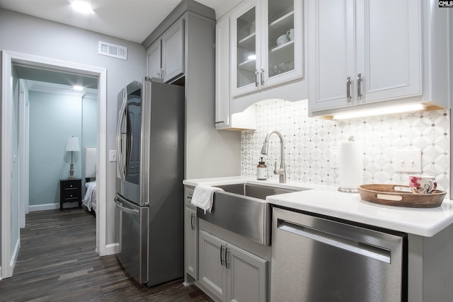 kitchen with sink, dark wood-type flooring, appliances with stainless steel finishes, gray cabinetry, and tasteful backsplash