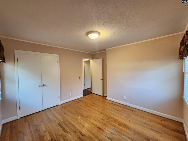 unfurnished bedroom featuring ornamental molding, light hardwood / wood-style flooring, and a textured ceiling