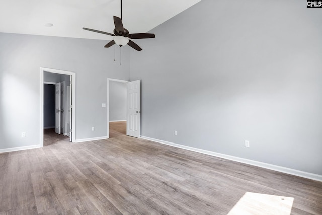 empty room with a towering ceiling, light hardwood / wood-style floors, and ceiling fan