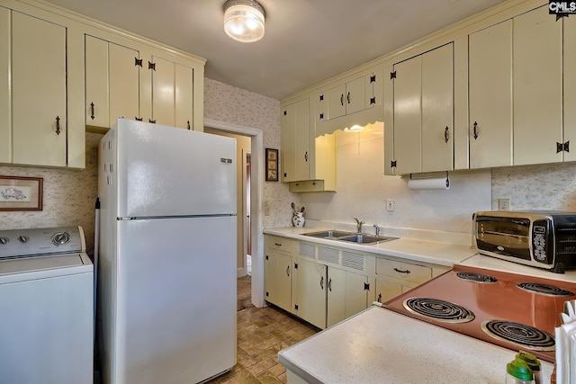 kitchen featuring washer / clothes dryer, sink, white refrigerator, stove, and cream cabinetry