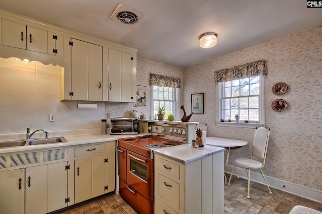 kitchen with white cabinetry, kitchen peninsula, sink, and electric range oven