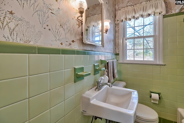 bathroom with sink, tile walls, and toilet