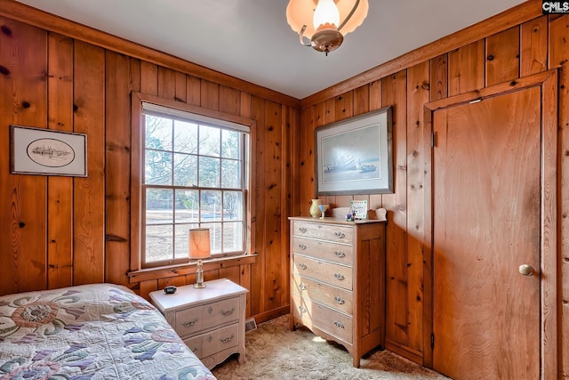 bedroom with light colored carpet and wooden walls