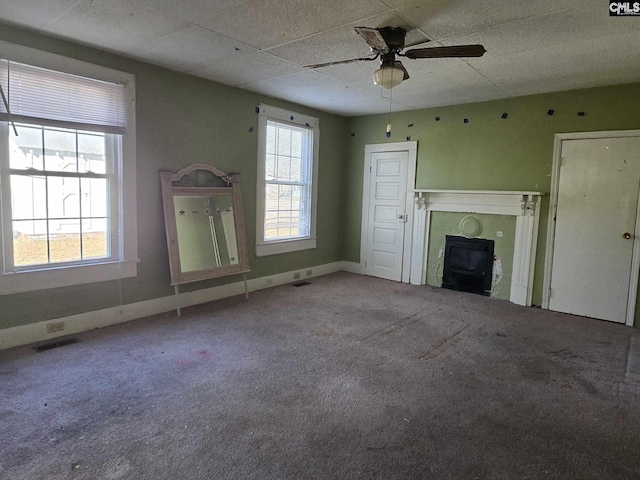 unfurnished living room with plenty of natural light, carpet floors, and ceiling fan