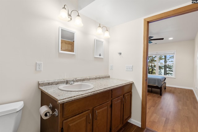 bathroom with hardwood / wood-style flooring, ceiling fan, vanity, and toilet