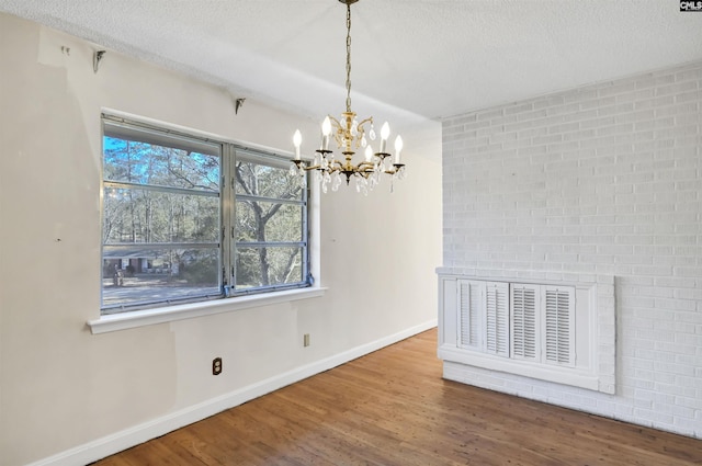 unfurnished dining area featuring hardwood / wood-style flooring, a chandelier, and a textured ceiling