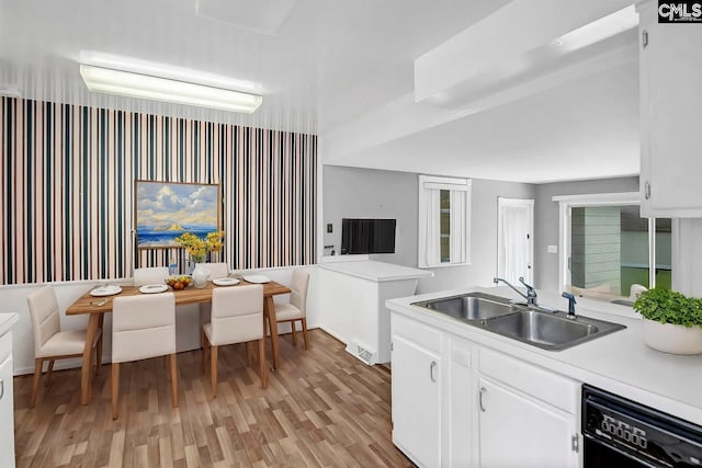 kitchen featuring white cabinetry, black dishwasher, sink, and light wood-type flooring