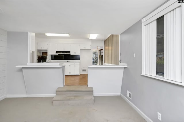 kitchen with white cabinetry, oven, sink, and kitchen peninsula