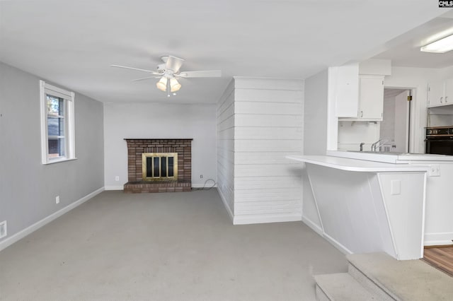 unfurnished living room with ceiling fan and a brick fireplace