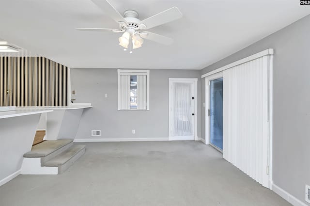 unfurnished living room featuring light colored carpet and ceiling fan