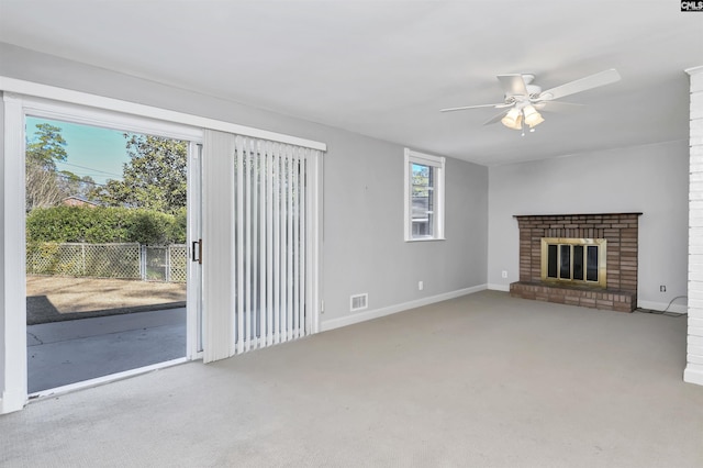 unfurnished living room with ceiling fan, light colored carpet, and a brick fireplace