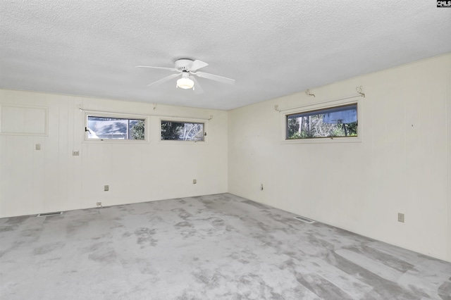 empty room with ceiling fan, light colored carpet, and a textured ceiling