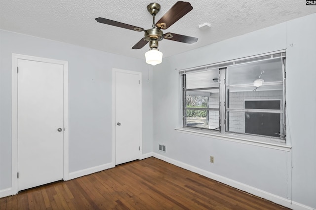 empty room with ceiling fan, dark hardwood / wood-style floors, and a textured ceiling