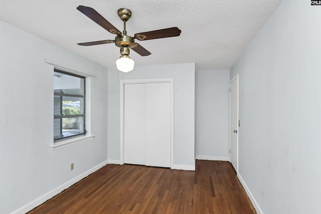 unfurnished bedroom featuring ceiling fan, a textured ceiling, dark hardwood / wood-style flooring, and a closet