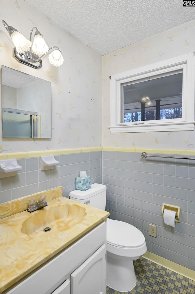 bathroom with tile walls, vanity, a textured ceiling, tile patterned floors, and toilet