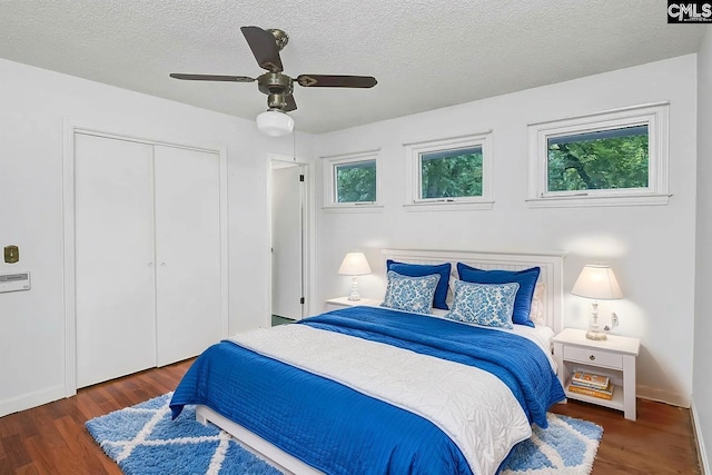 bedroom with ceiling fan, dark wood-type flooring, a textured ceiling, and a closet