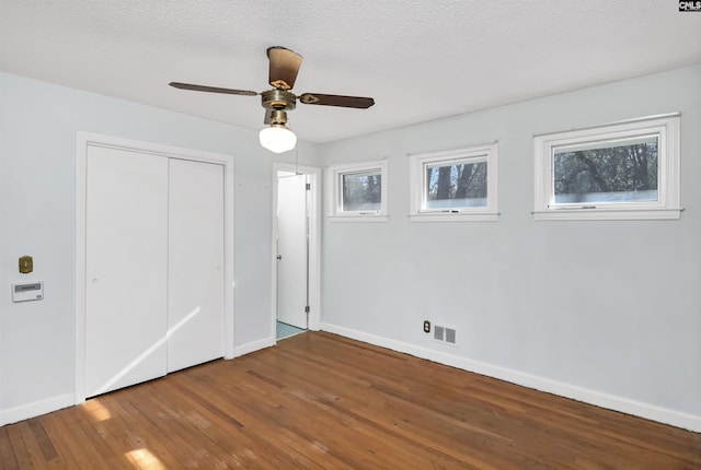 unfurnished bedroom featuring ceiling fan, hardwood / wood-style floors, a textured ceiling, and a closet