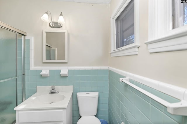 bathroom featuring vanity, toilet, a shower with shower door, and tile walls