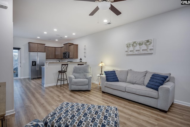 living room featuring ceiling fan and light wood-type flooring